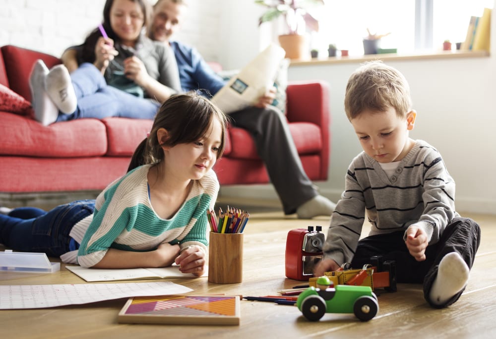 Family with children playing on the ground with toys