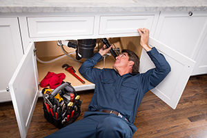 plumber laying down under sink for sink pipe repair