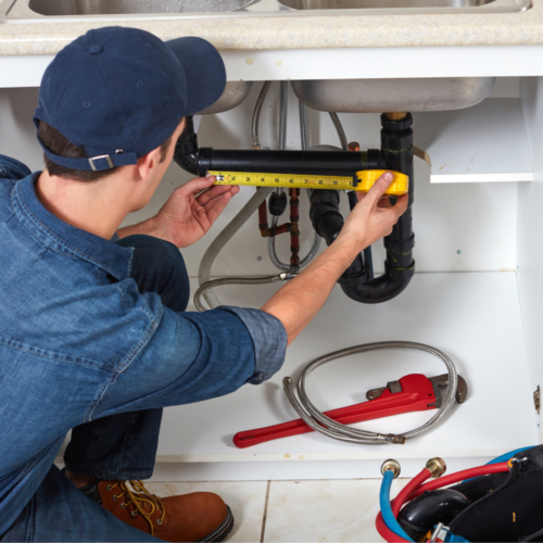 a absolute contractor measuring out pipes under sink